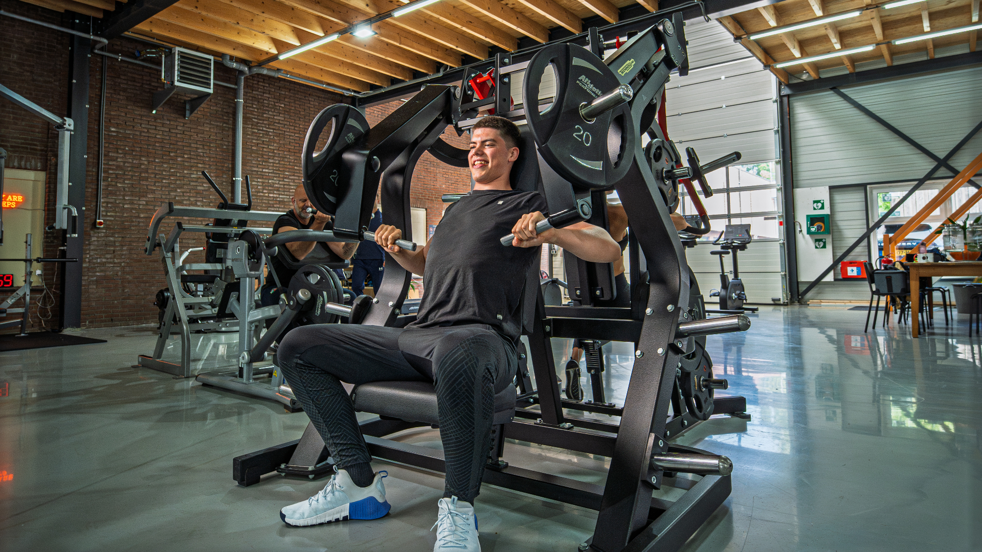 Lid traint aan een drukmachine in de gym van THE LAB Fitness Weesp